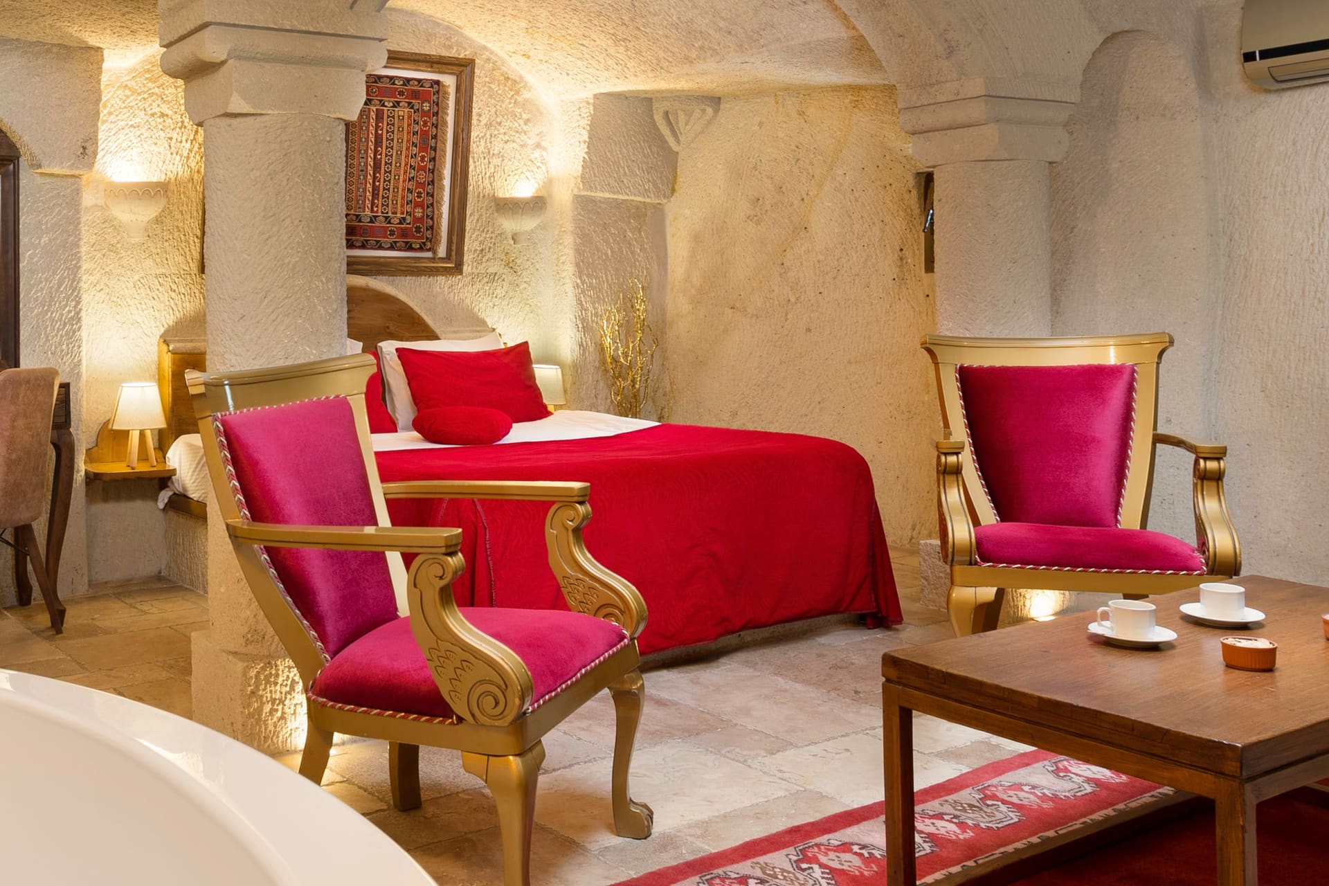 Room 115, Junior Cave Suite: close view of the burgundy chair, bathtub and bed behind