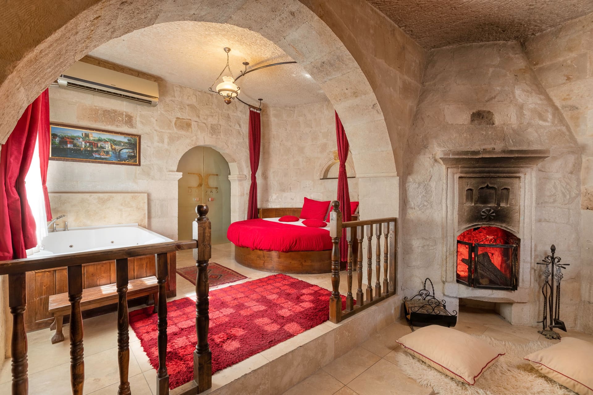 Room 107, King Suite: red beds on the railed raised platform with the fireplace nearby