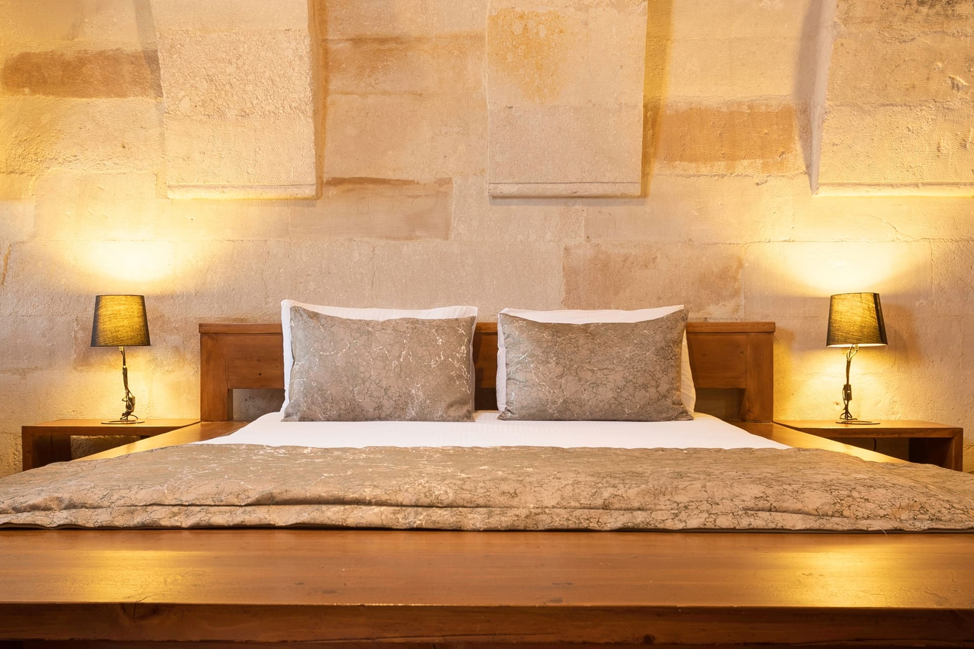 Room 108, Junior Suite: Close-up of bed, arched stone wall, pillows, lamps.