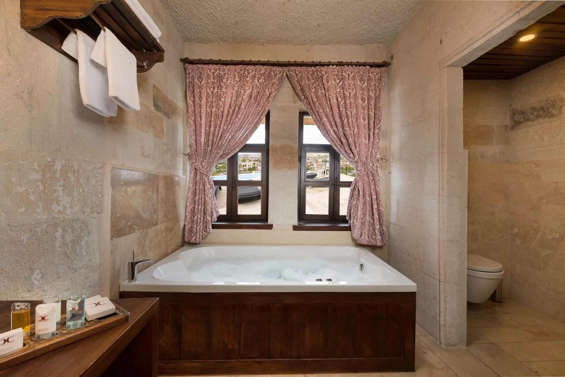 Room 105, King Suite: the jacuzzi tub beneath the curtained window with the toilet behind it