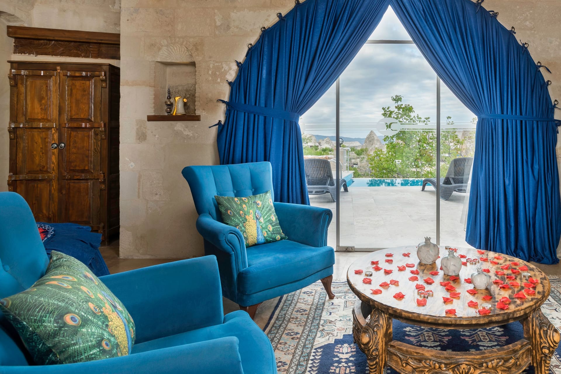 Room 120, Queen Suite: Round table with blue armchairs, curtain opening onto the terrace.
