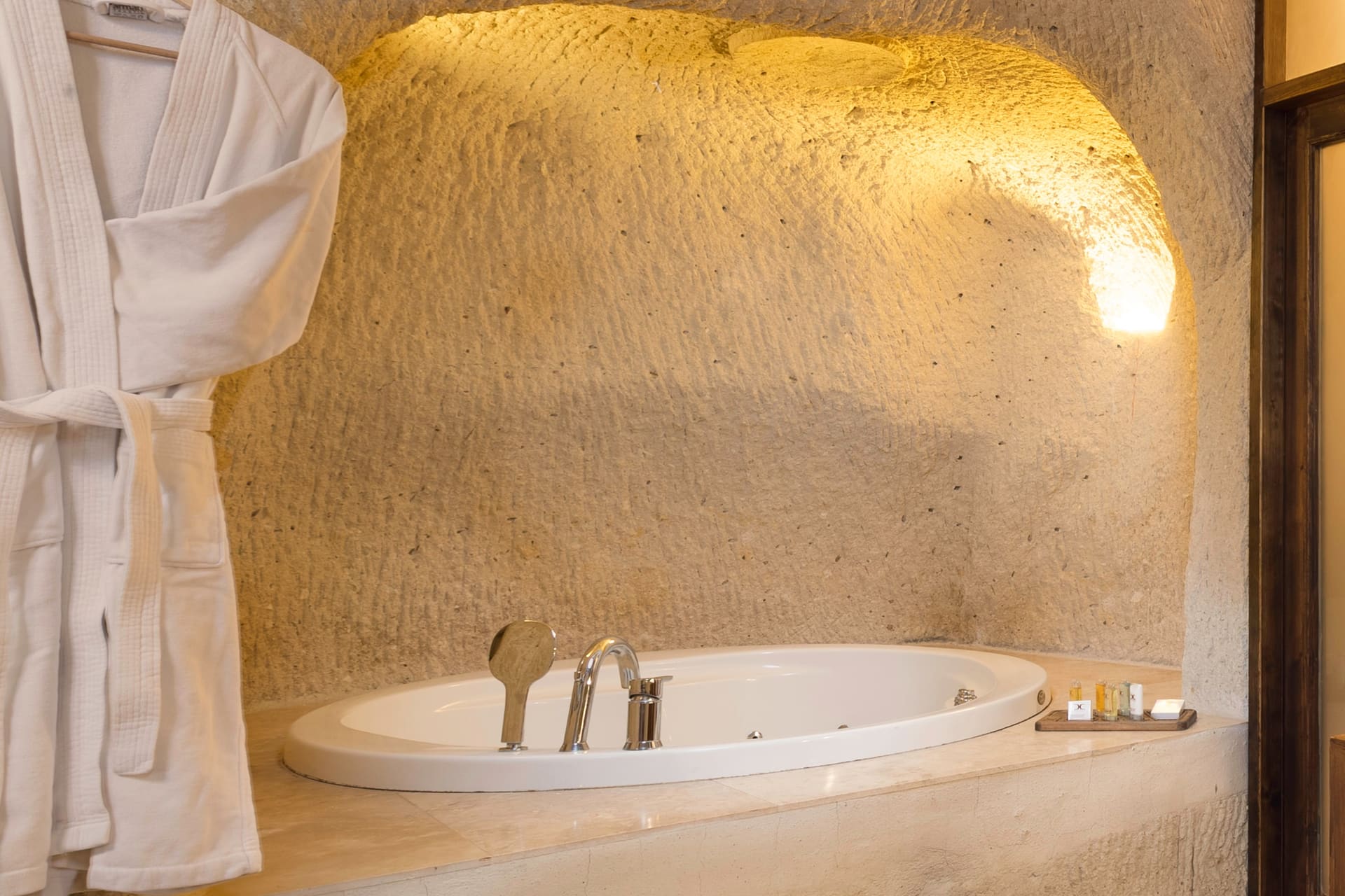 Room 113, Junior Cave Suite: close view of the bathtub, arched stone wall, candles along the edge