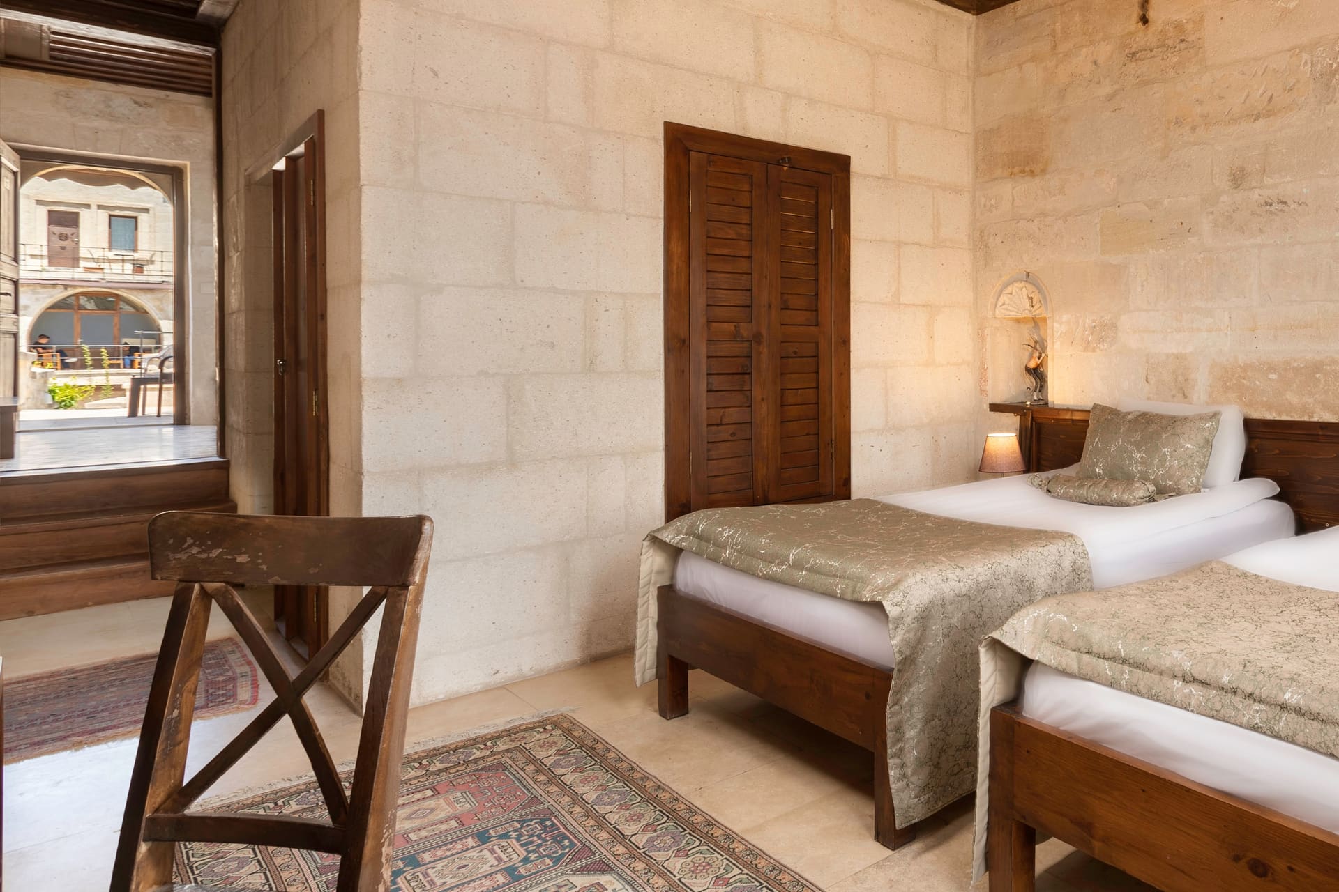 Room 117, Junior Suite: Twin beds, wooden shuttered door, courtyard view through window.