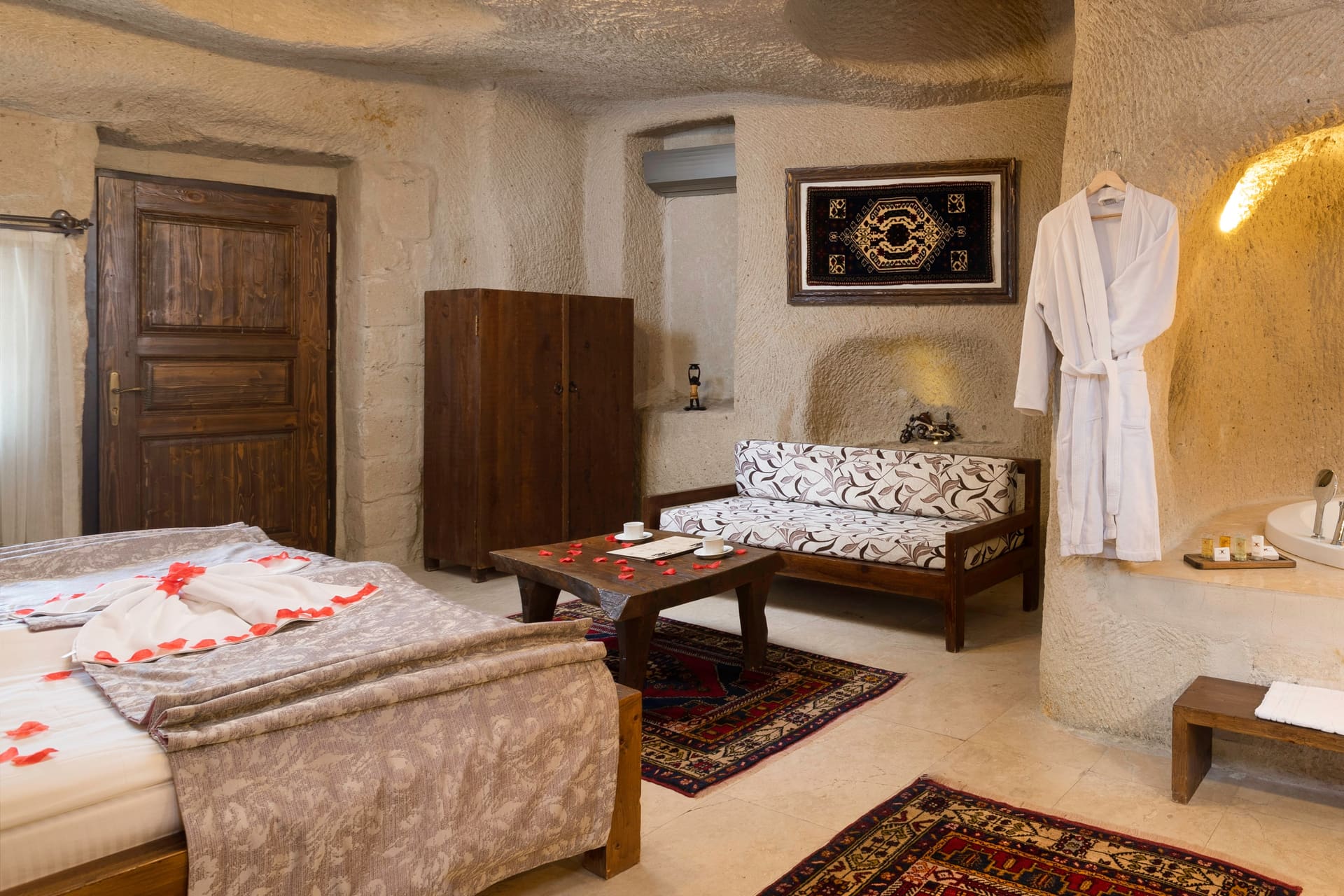 Room 113, Junior Cave Suite: bed, wardrobe, robe hanging in the stone alcove