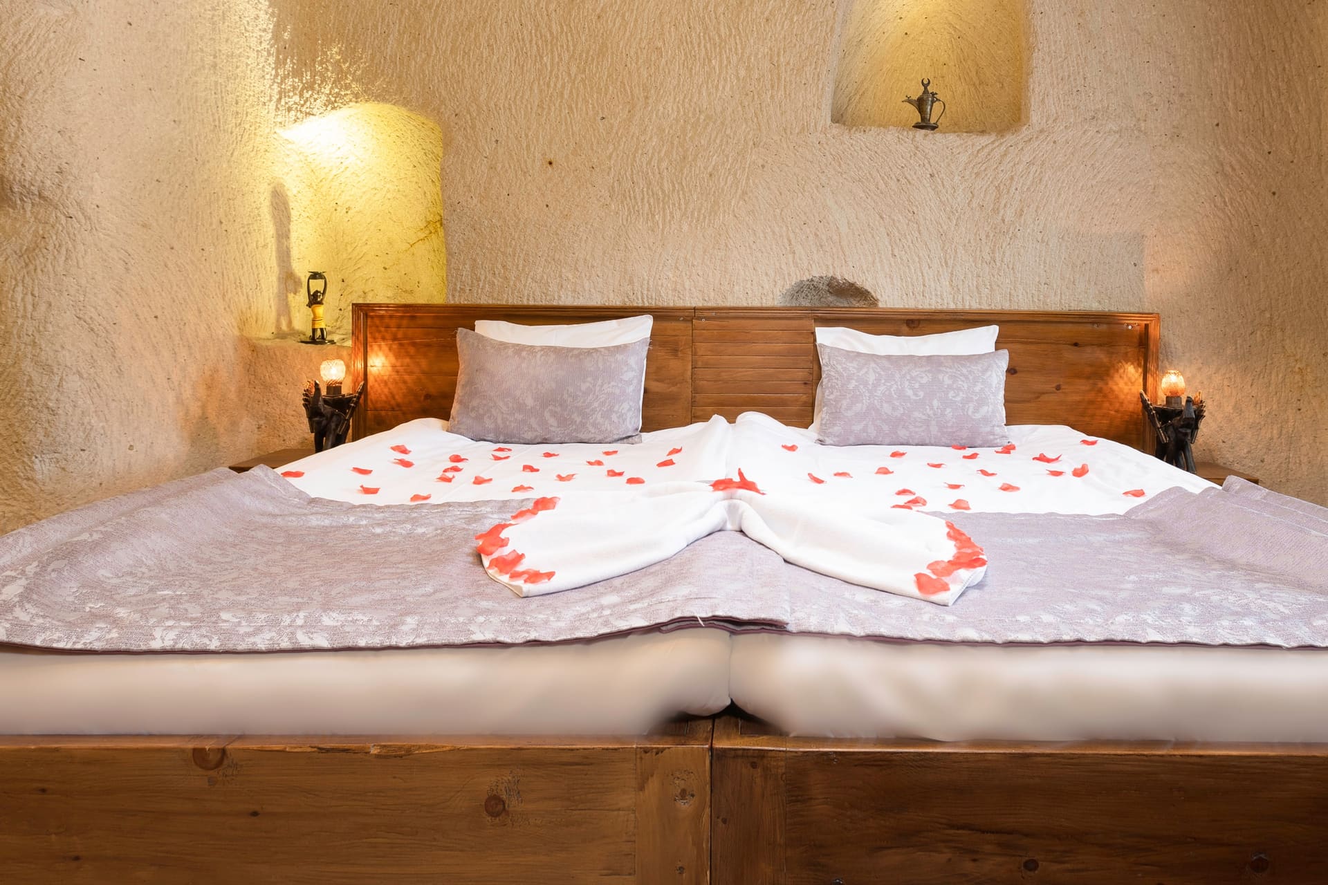 Room 113, Junior Cave Suite: bed from a side angle, folded-towel decoration and rose petals