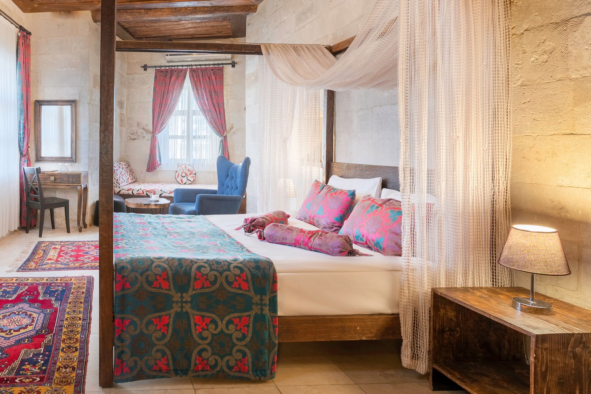 Room 102, Junior Suite: Sheer-draped canopy bed, curtained window, blue accent chair.