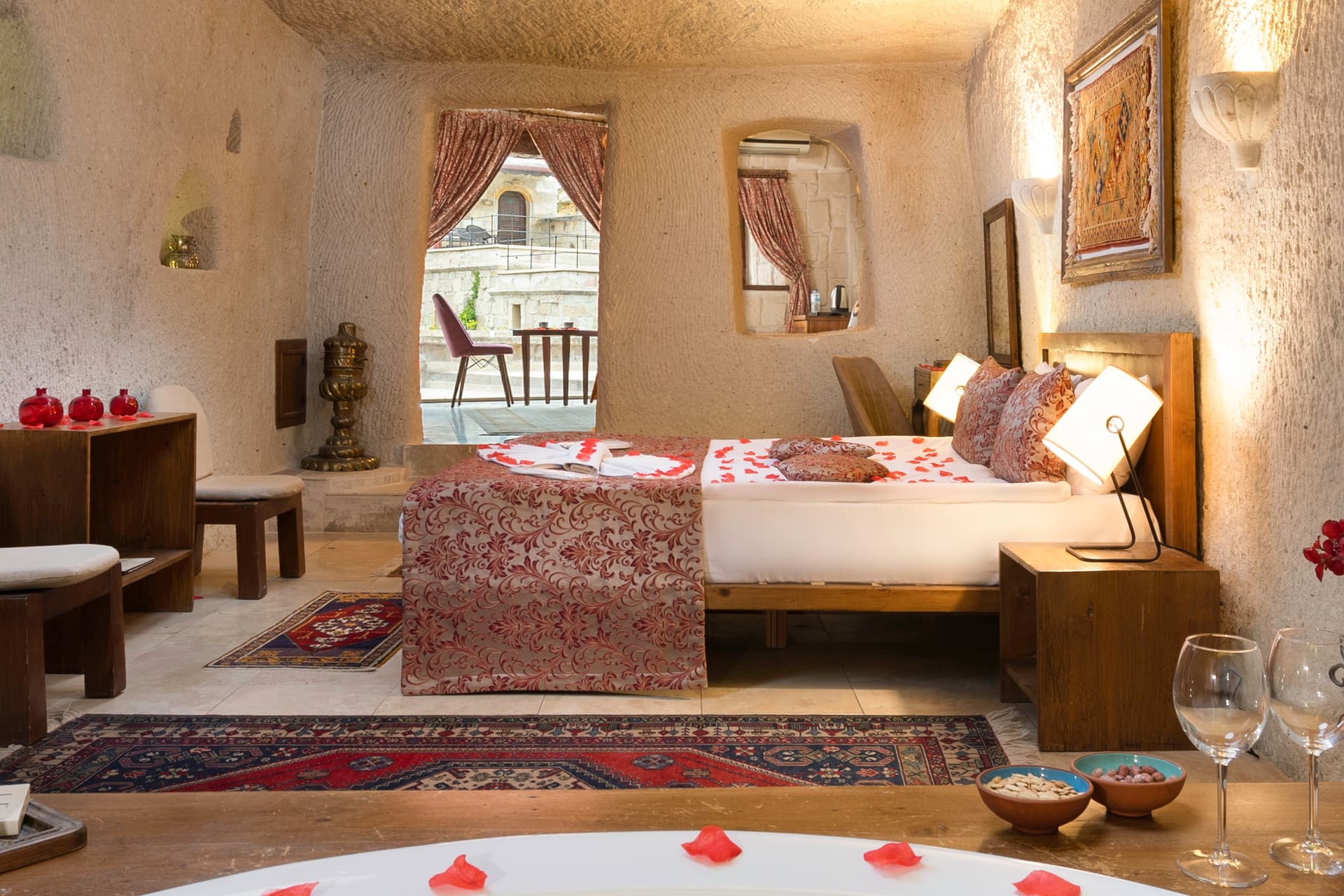 Room 111, King Cave Suite: close view of the bed, the terrace door behind it, and a woven rug artwork on the wall