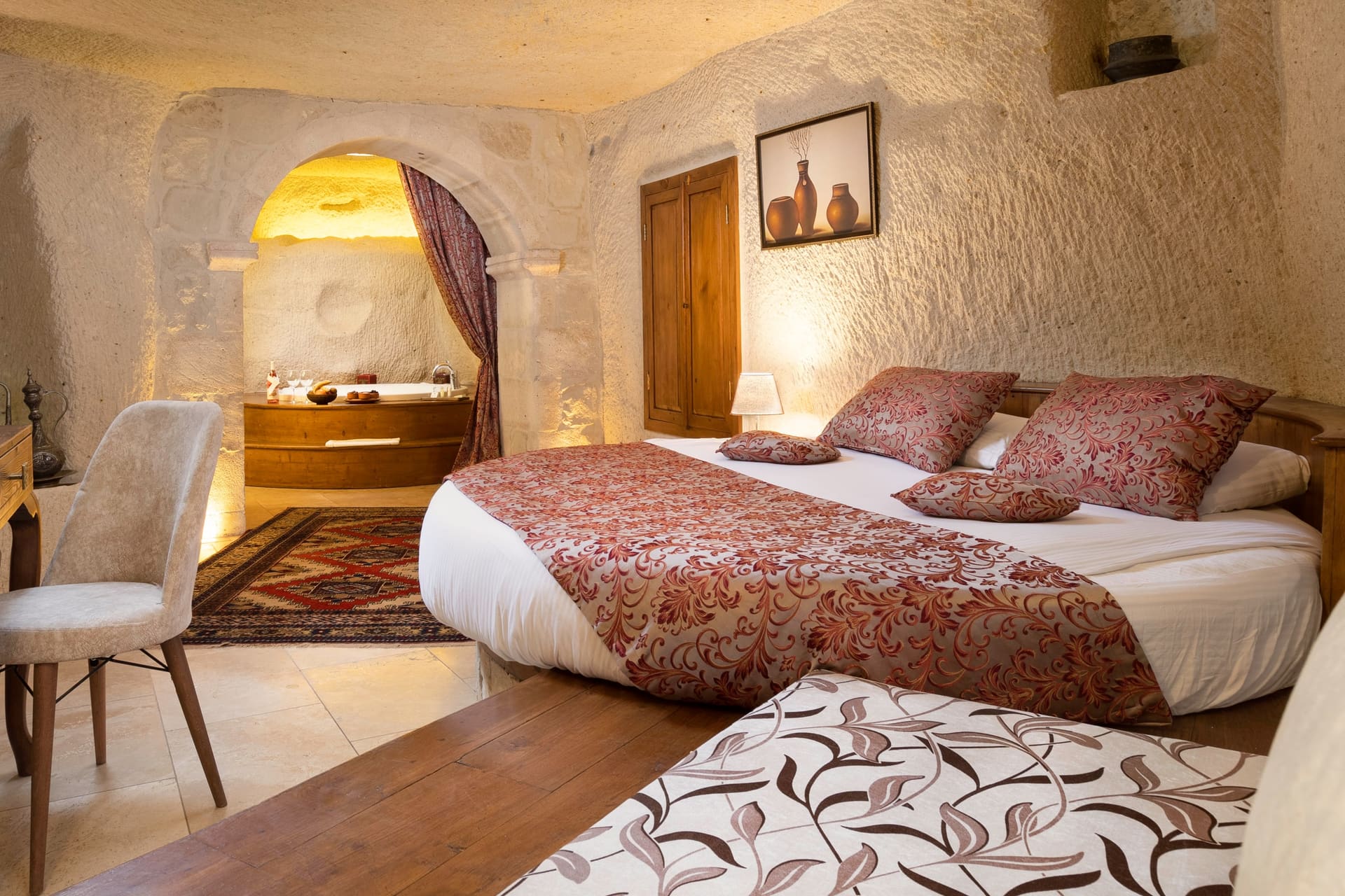 Room 112, King Cave Suite: wide view of the bed, the arched jacuzzi niche, and the wooden wardrobe door