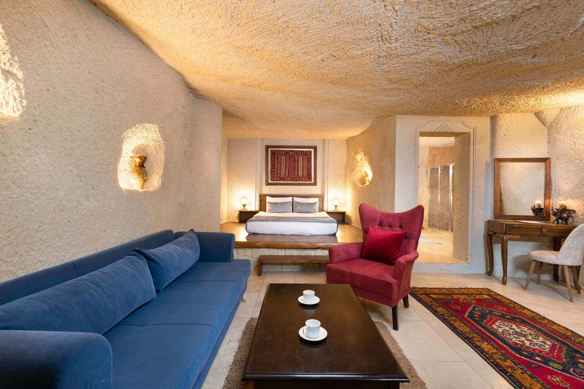 Room 114, Junior Cave Suite: seating area, bed behind, mirrored dressing table on the right