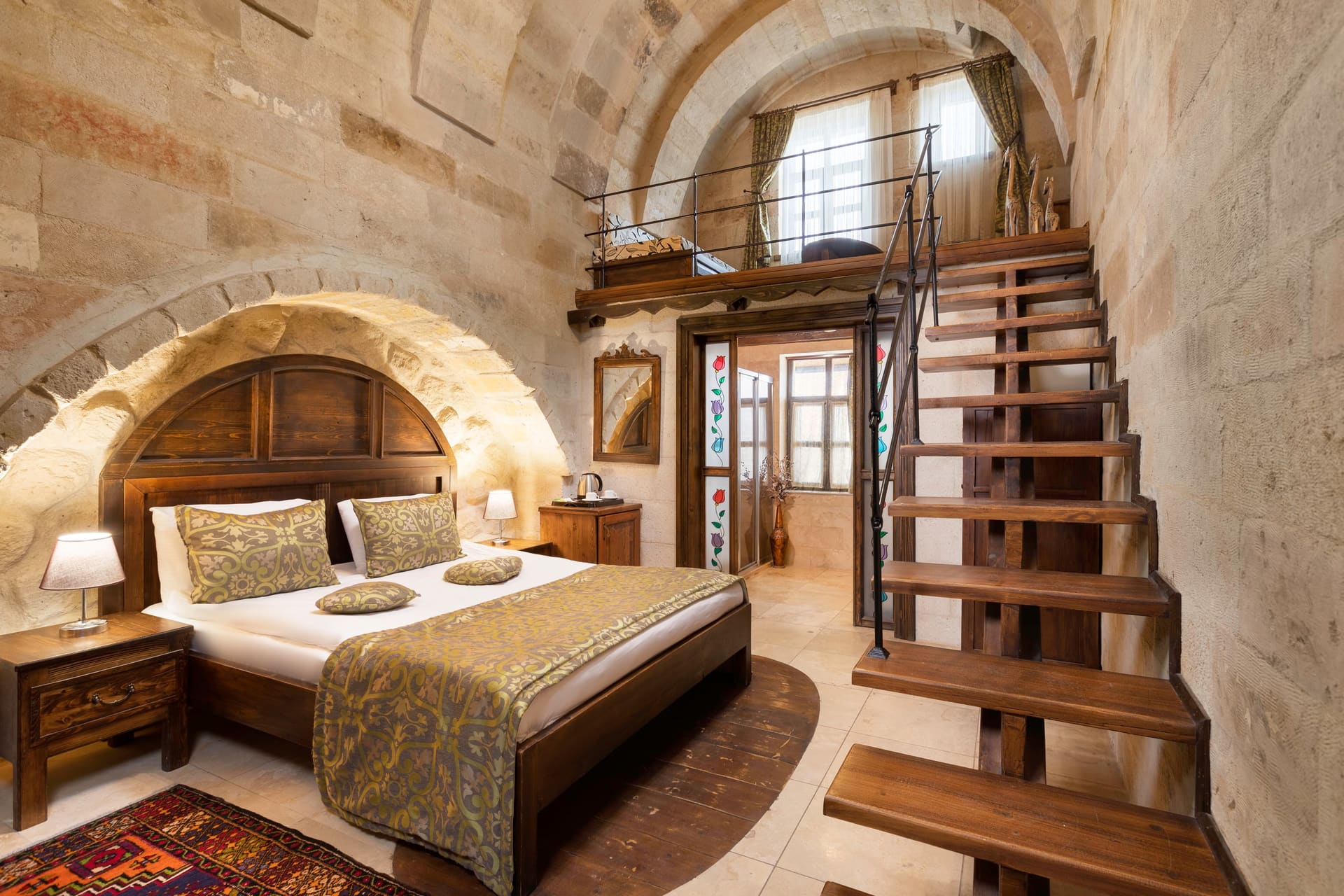 Room 104, Junior Suite: Close-up of arched bed alcove, patterned bedspread, staircase behind.