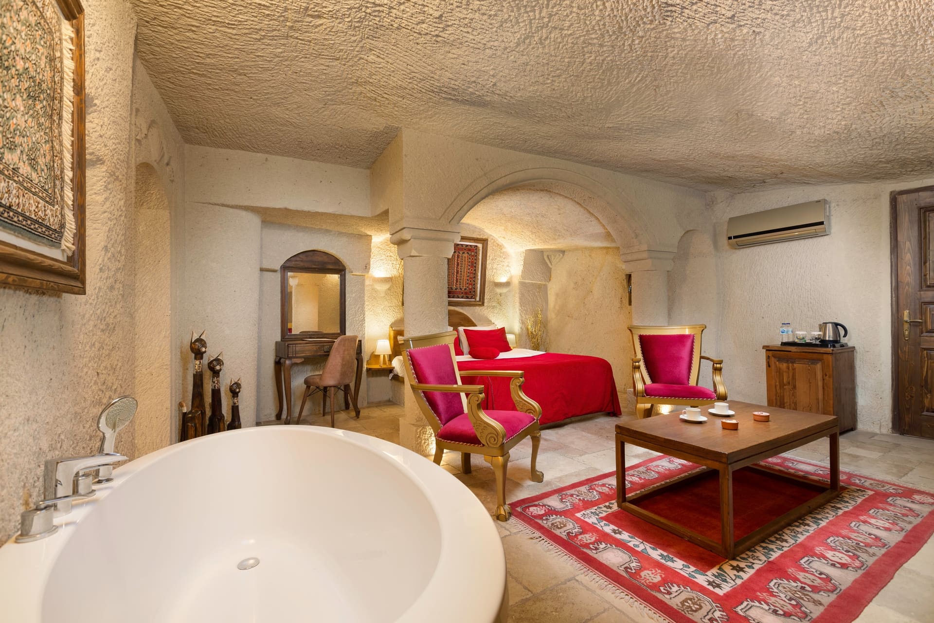 Room 115, Junior Cave Suite: bathtub in the foreground, wardrobe and bed behind, rug