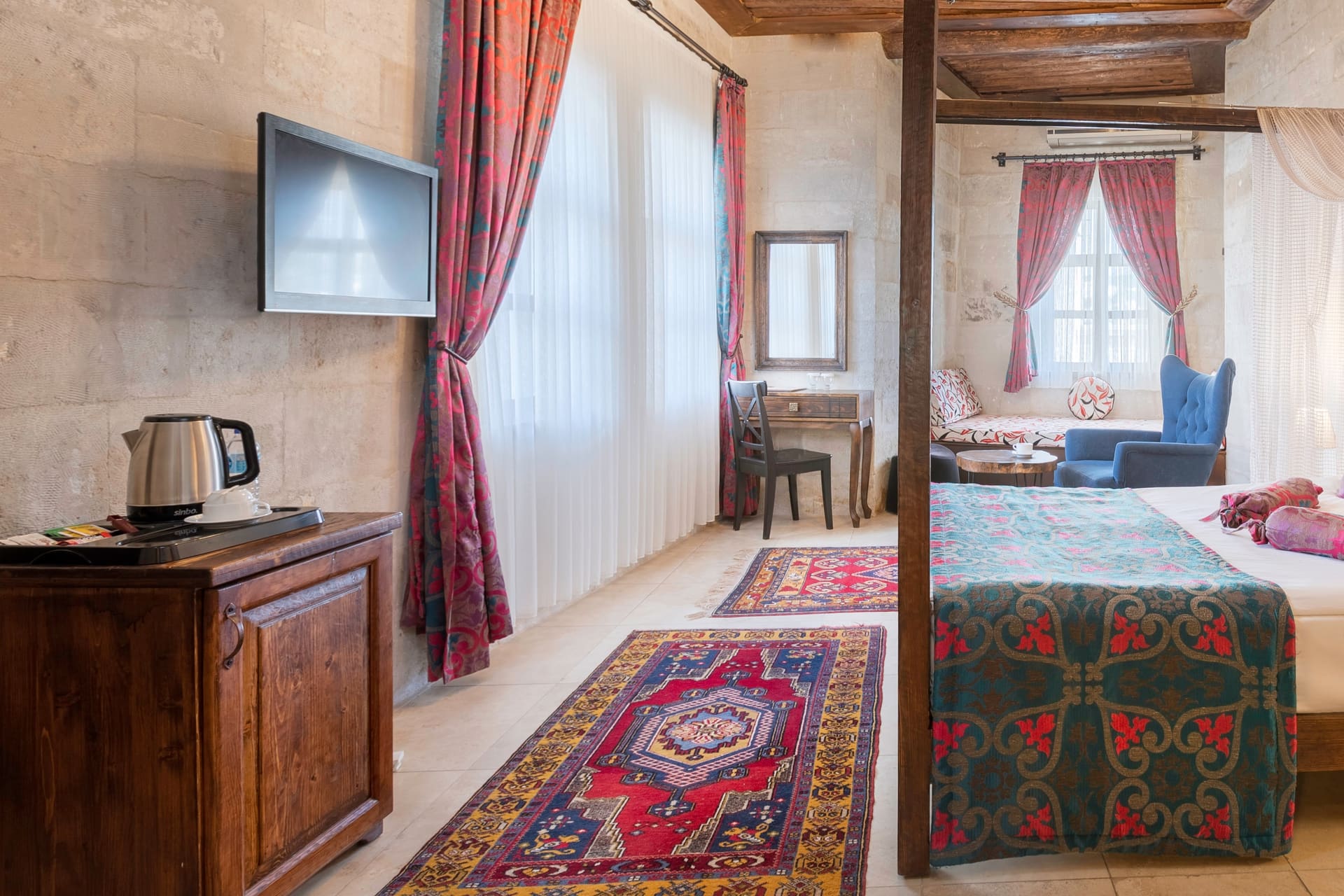 Room 102, Junior Suite: Wall-mounted TV, kettle on wooden chest, curtained window.