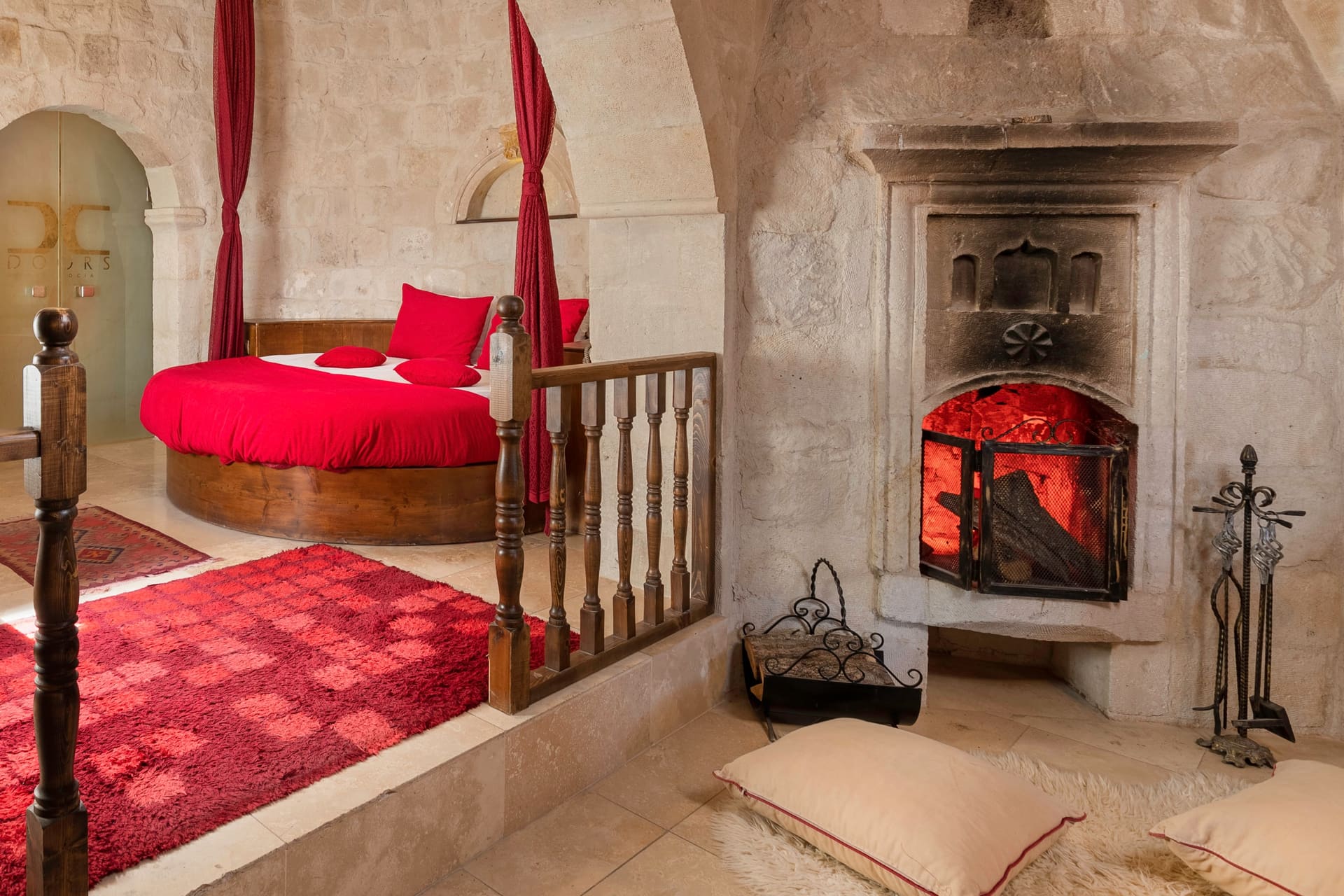 Room 107, King Suite: the round red bed on the railed platform with the fireplace and wall decoration
