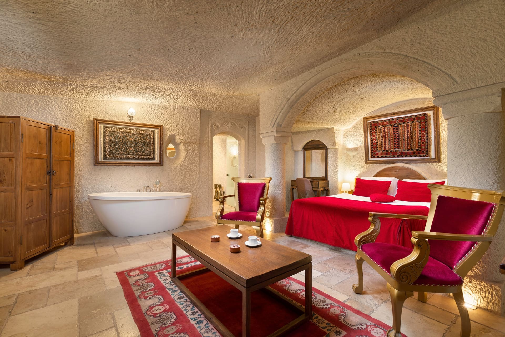 Room 115, Junior Cave Suite: freestanding oval bathtub in the foreground, bed and chairs behind