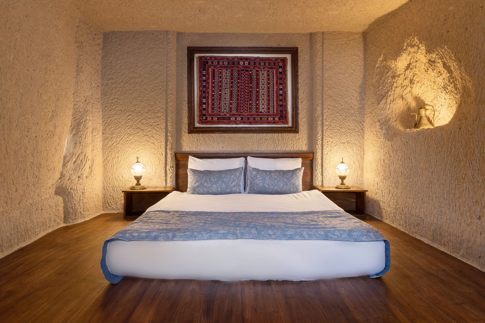 Room 114, Junior Cave Suite: low platform bed viewed head-on, wooden floor