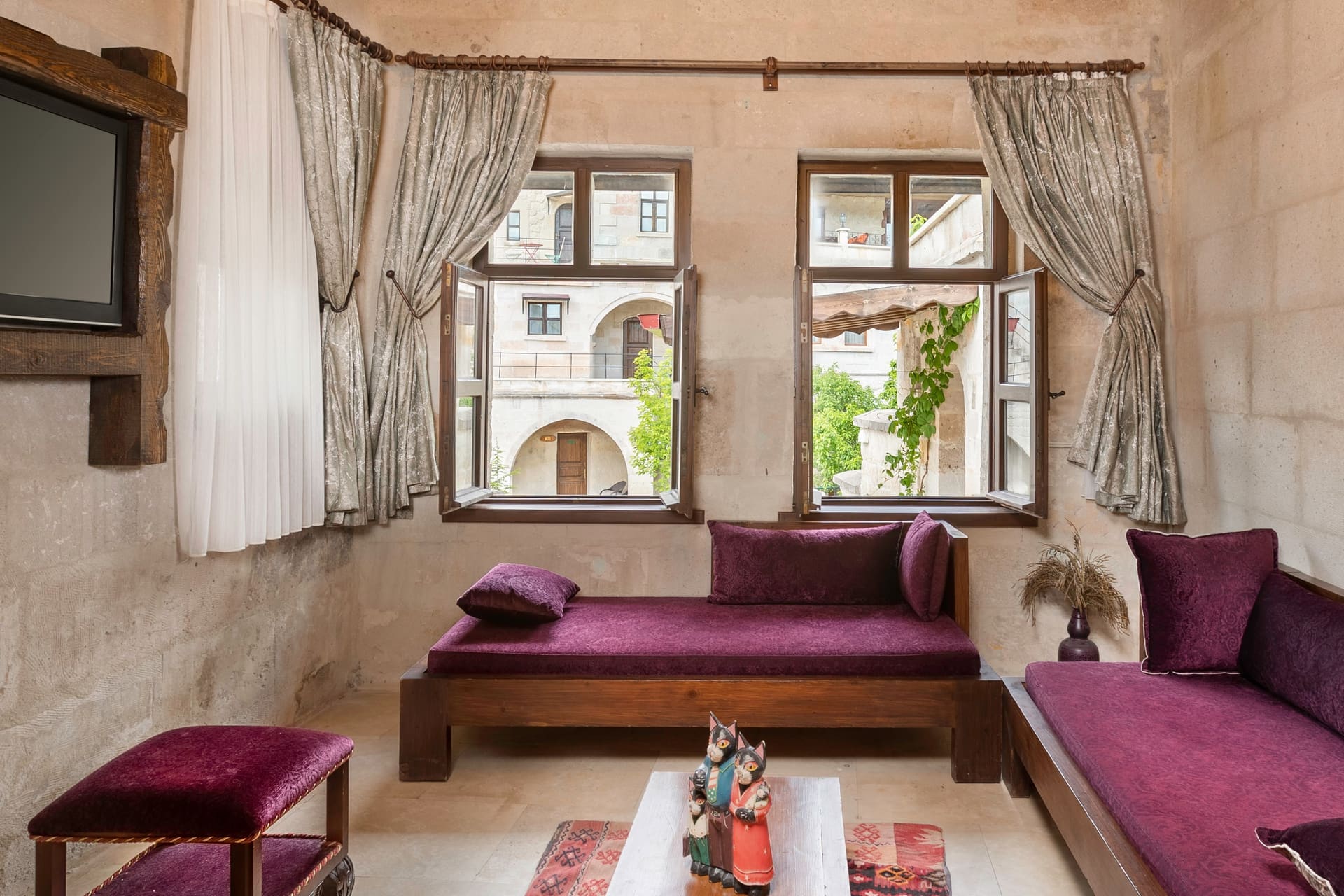 Room 117, Junior Suite: Purple sofas, arched windows overlooking greenery, coffee table.