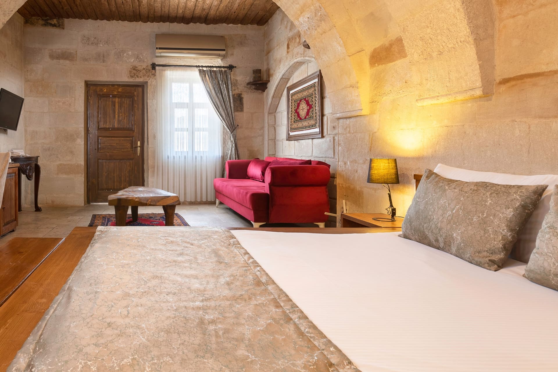Room 108, Junior Suite: Wood-based bed, curtained window, wall-mounted TV, wooden door.